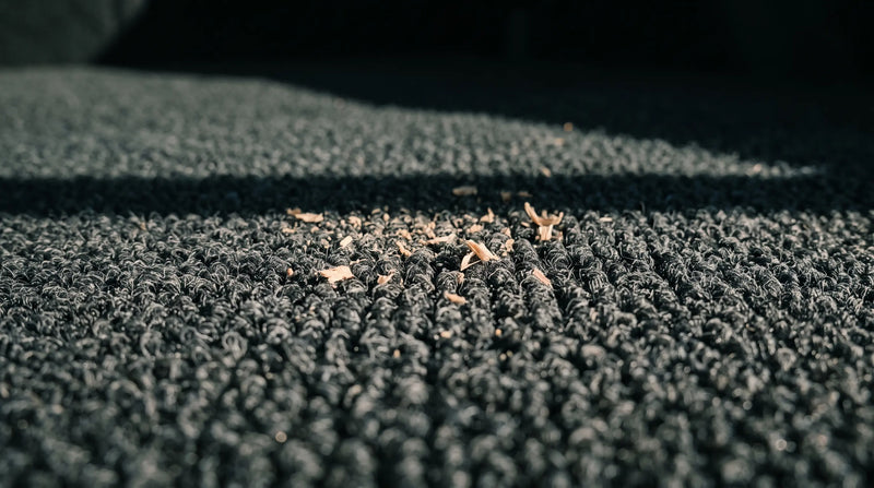 Low angle close-up of automotive trunk carpet pile with a defined band of shadow across it.