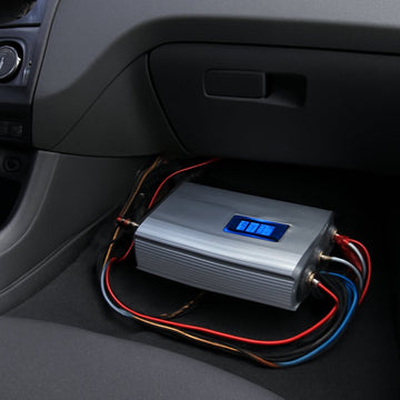 A modern car interior with a visible under‑dash amplifier installation, highlighting wiring and a digital display showing power output. Alt: Determining power requirements for car audio amplifiers