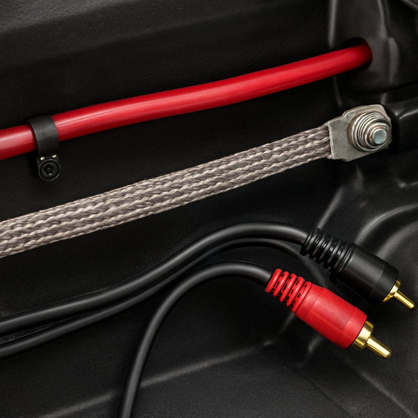 A close‑up of a car audio installation showing power wire, ground strap, and RCA cables neatly separated. Alt: diagnosing alternator whine with proper wiring layout