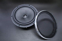 Two speakers, one with a mesh grill and one without, on a dark background