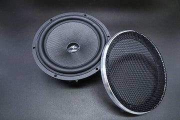 Two speakers, one with a mesh grill and one without, on a dark background