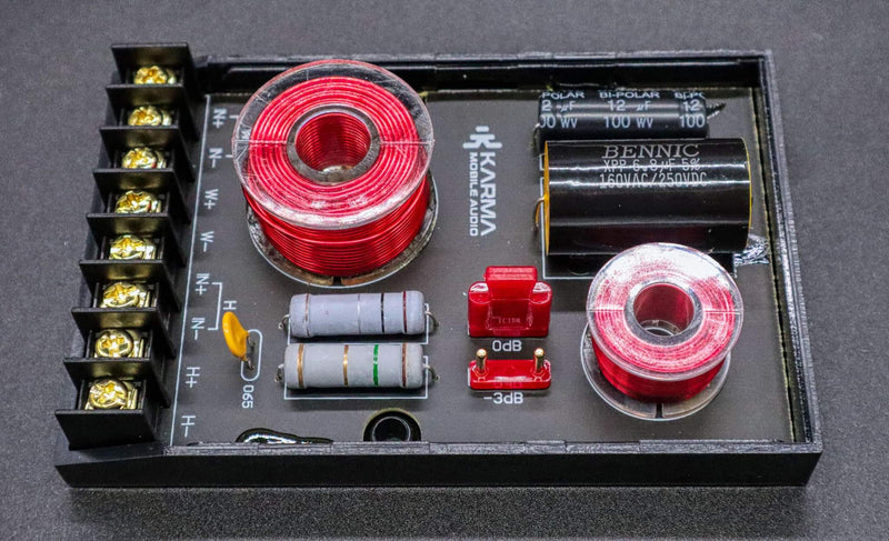 Electronic component board with red and silver coils, capacitors, and connectors on a dark background