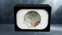 Marble-like material sample in a black and white display case on a gray background
