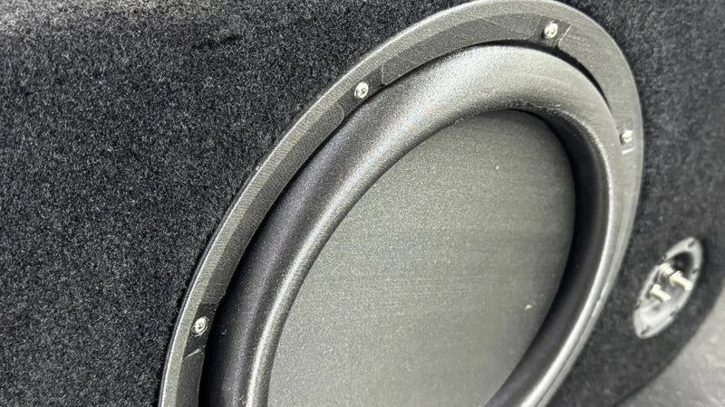 Close-up of a car subwoofer in a black enclosure