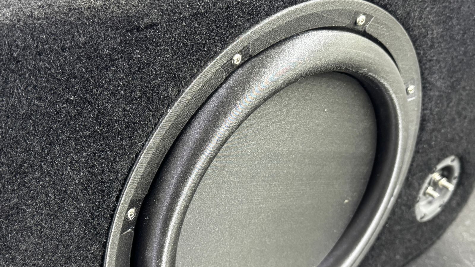 Close-up of a car subwoofer in a black enclosure