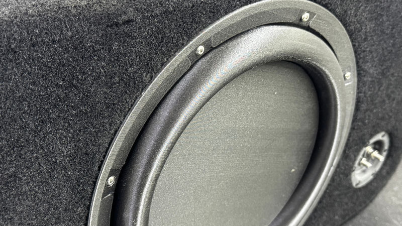 Close-up of a car subwoofer in a black enclosure