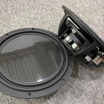 Stereo Integrity BM-11 shallow subwoofers, one showing the flat carbon fiber piston and one showing the side profile