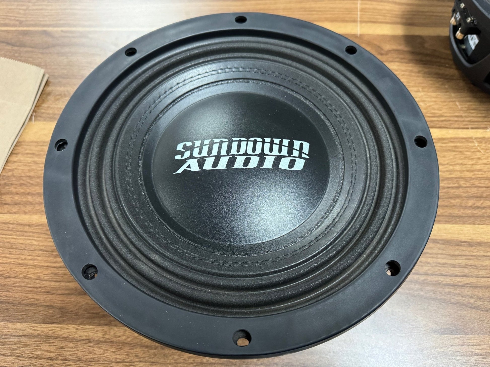 Black speaker cone with 'Sundown Audio' logo on a wooden surface